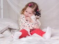 Baby girl is sitting on bed and hugging dog Royalty Free Stock Photo