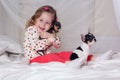 Baby girl is sitting on bed and hugging small dog Royalty Free Stock Photo