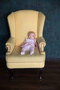 Baby Girl Sitting on Big Armchair in Studio