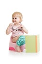 Baby girl sitting on chamberpot with book Royalty Free Stock Photo