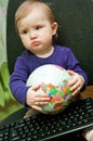 Baby girl sitting with computer keyboard and a globe