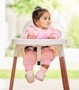 Baby, girl and sitting in feeding chair with thinking, curious and calm expression in home or apartment. Child, kid and