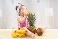 Baby girl sitting among fruits, eating lemon Royalty Free Stock Photo