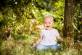 Baby girl sitting on grass in garden under small Apple tree. gardening. Royalty Free Stock Photo