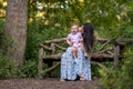 Baby girl sitting on mother`s lap on wooden bench Royalty Free Stock Photo