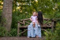 Baby girl sitting on mother`s lap on wooden bench Royalty Free Stock Photo