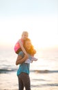 Baby girl sitting on shoulders of mother on beach