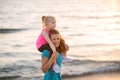 Baby girl sitting on shoulders of mother on beach