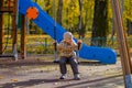 Baby girl sitting on a swing on a playground in an autumn park Royalty Free Stock Photo