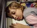 The baby girl is sleeping soundly and opened her mouth. The kid is dressed in pajamas, colorful bedding is put on a pillow and Royalty Free Stock Photo