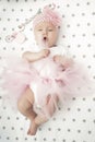 Baby girl smiling with round cheeks, a fluffy pink skirt and a flower on her head. learning newborn Royalty Free Stock Photo