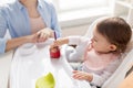 Baby girl with spoon eating puree from jar at home Royalty Free Stock Photo