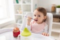 Baby girl with spoon eating puree from jar at home Royalty Free Stock Photo