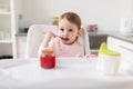 Baby girl with spoon eating puree from jar at home Royalty Free Stock Photo