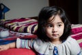 Baby girl standing with bed.