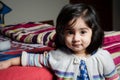 Baby girl standing with bed.