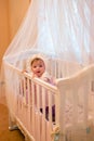 Baby girl standing in her crib. Royalty Free Stock Photo