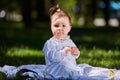 Baby girl in summer dress sitting in the green meadow in the city park. Royalty Free Stock Photo