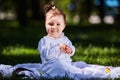 Baby girl in summer dress sitting in the green meadow in the city park. Royalty Free Stock Photo