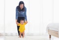 Baby girl taking first steps learning to walk with mom