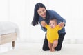 Baby girl taking first steps learning to walk with mom