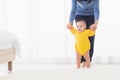 Baby girl taking first steps learning to walk with mom