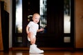 Baby girl trying to put on a big white sneaker of an adult Royalty Free Stock Photo