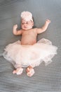 baby girl in tutu and pink ballet slippers lying on a gray blanket Royalty Free Stock Photo