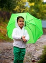 Baby girl with an umbrella in the rain runs through the puddles Royalty Free Stock Photo