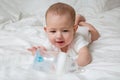 Baby girl wants to drink and pull hands to plastic bottle of water. White background