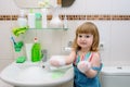 baby girl washing her face, washing her hands and brushing her teeth. morning hygiene. in the white bathroom at home Royalty Free Stock Photo