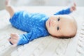 Baby girl wearing blue clothes relaxing in bedroom