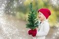 Baby Girl Wearing Mittens Holding Small Christmas Tree with Snow Effe Royalty Free Stock Photo