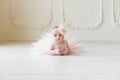 Baby girl wearing a peach tutu. Cute smiling baby girl lying on the floor on creamy background Royalty Free Stock Photo