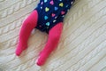 Baby girl wearing pink tights and colorful onesie