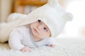 Baby girl wearing white towel or winter overal in white sunny bedroom Royalty Free Stock Photo