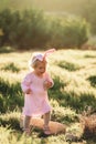 Baby girl wears rabbit ears, walking in grass Royalty Free Stock Photo