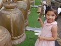 A baby girl, 3 years old, enjoys ringing big temple bells as the sound of the bell is considered auspicious Royalty Free Stock Photo