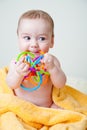 Baby Gnawing Multicolored Toy on Yellow Towel Royalty Free Stock Photo