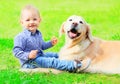 Baby and Golden Retriever dog is sitting together on the grass Royalty Free Stock Photo