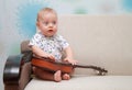 Baby with guitar sit on couch Royalty Free Stock Photo