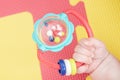 Baby hand holding a rattle on a colored rubber mat puzzle for playing foam with geometric figures