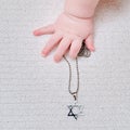 Baby hand and Jewish religious symbol is the star of David, close-up. Children fingers and an object on a white background
