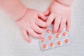 Baby hand and medicines tablets in a package, close-up. Children fingers and an object on a white background Royalty Free Stock Photo