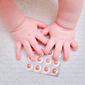 Baby hand and medicines tablets in a package, close-up. Children fingers and an object on a white background Royalty Free Stock Photo