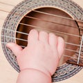 Baby hand and musical instrument guitar, close-up. Children fingers and an object on a white background Royalty Free Stock Photo