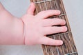 Baby hand and musical instrument guitar, close-up. Children fingers and an object on a white background Royalty Free Stock Photo