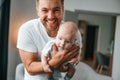 With baby in hands. Smiling, having fun. Father with toddler is at home, taking care of his son Royalty Free Stock Photo