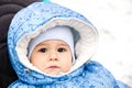 Baby happy laughing enjoying a walk in a snowy winter park sitting in a warm stroller with sheepskin hood Royalty Free Stock Photo