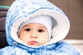 Baby happy laughing enjoying a walk in a snowy winter park sitting in a warm stroller with sheepskin hood Royalty Free Stock Photo